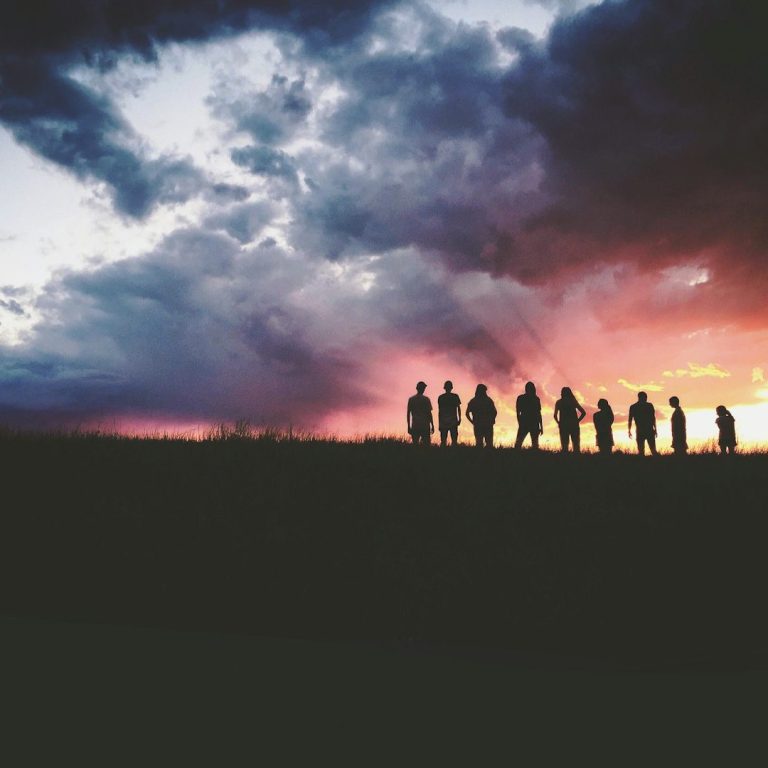 Group of People on Hillside Looking Over the Sunset