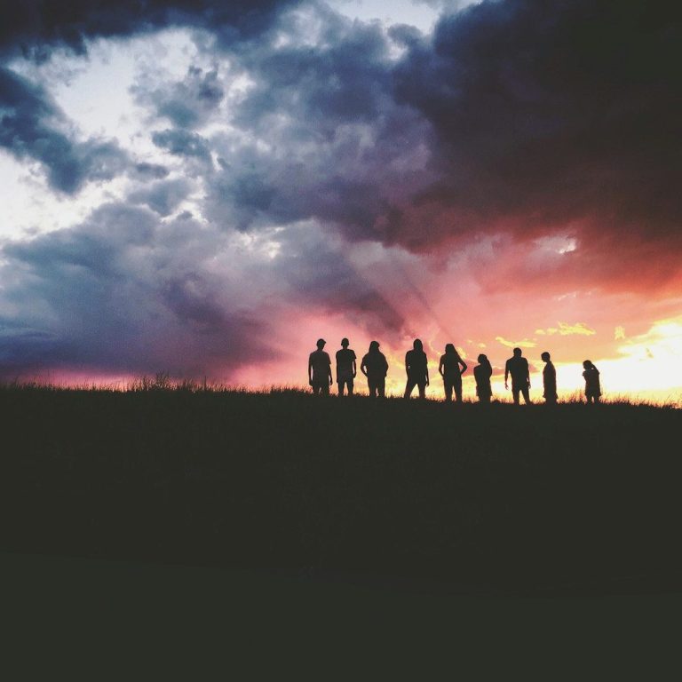 Group of People on Hillside Looking Over the Sunset