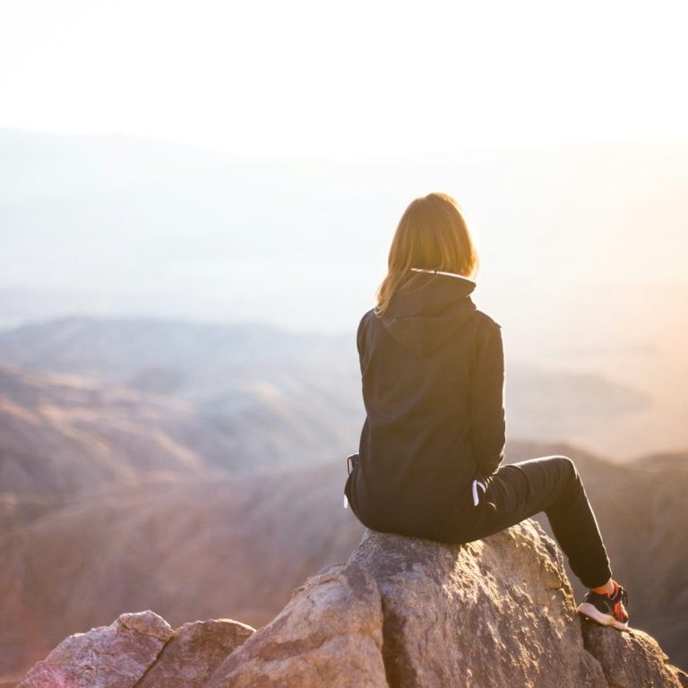Woman in black Hiking Outfit Sitting on Mountain Looking Outward